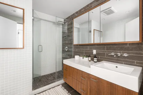 a bathroom with a double vanity sink mirror and shower
