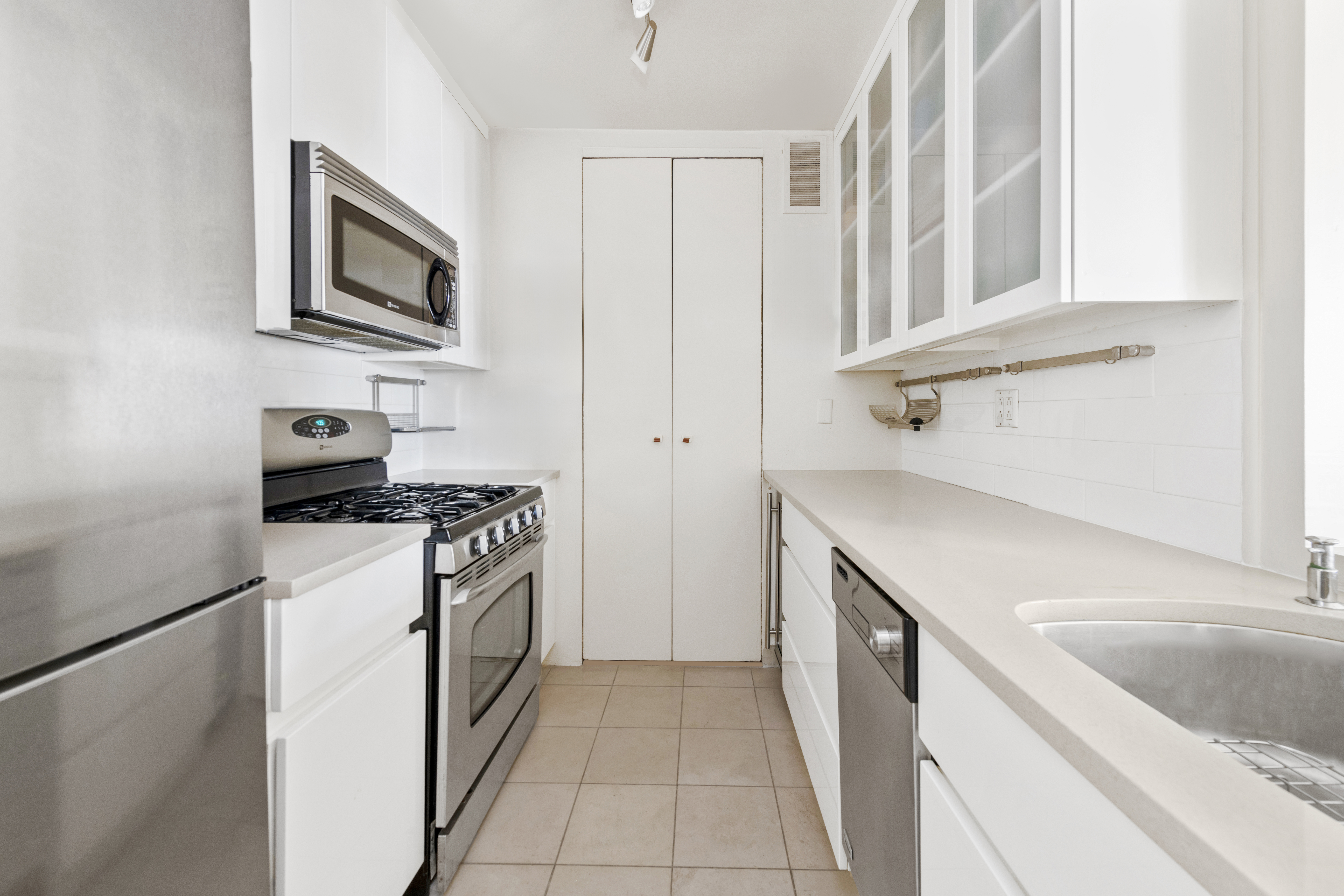 350 West 50th Street, Unit 15F Manhattan, NY 10019 - Photo 5 of 8 a kitchen with stainless steel appliances granite countertop a sink stove and refrigerator