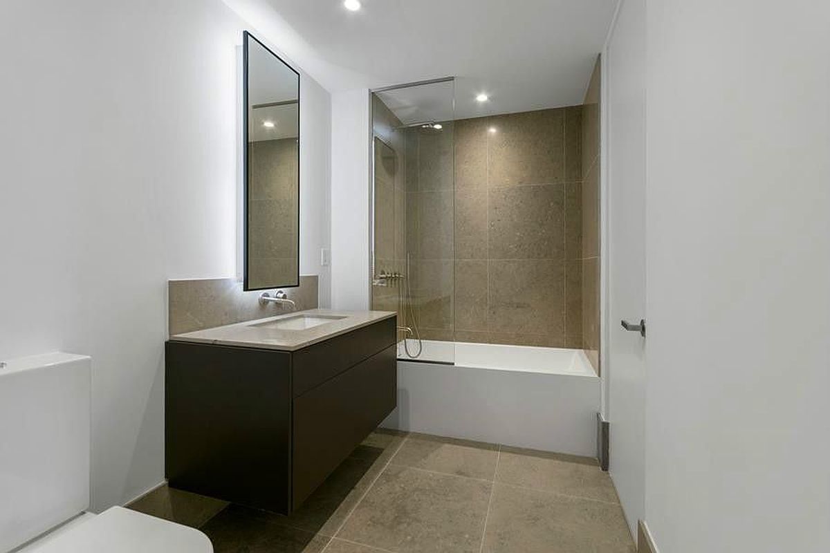 429 Kent Avenue, Unit 607 Brooklyn, NY 11249 - Photo 7 of 14 a bathroom with a bathtub sink mirror and toilet