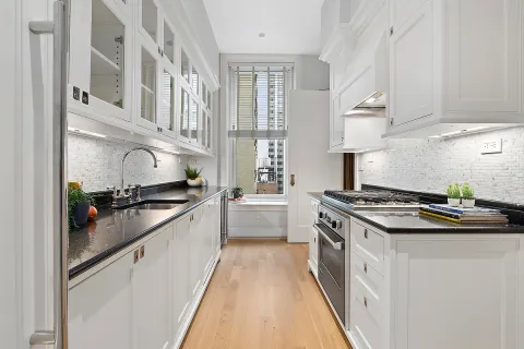 a large white kitchen with stainless steel appliances granite countertop a stove and a sink
