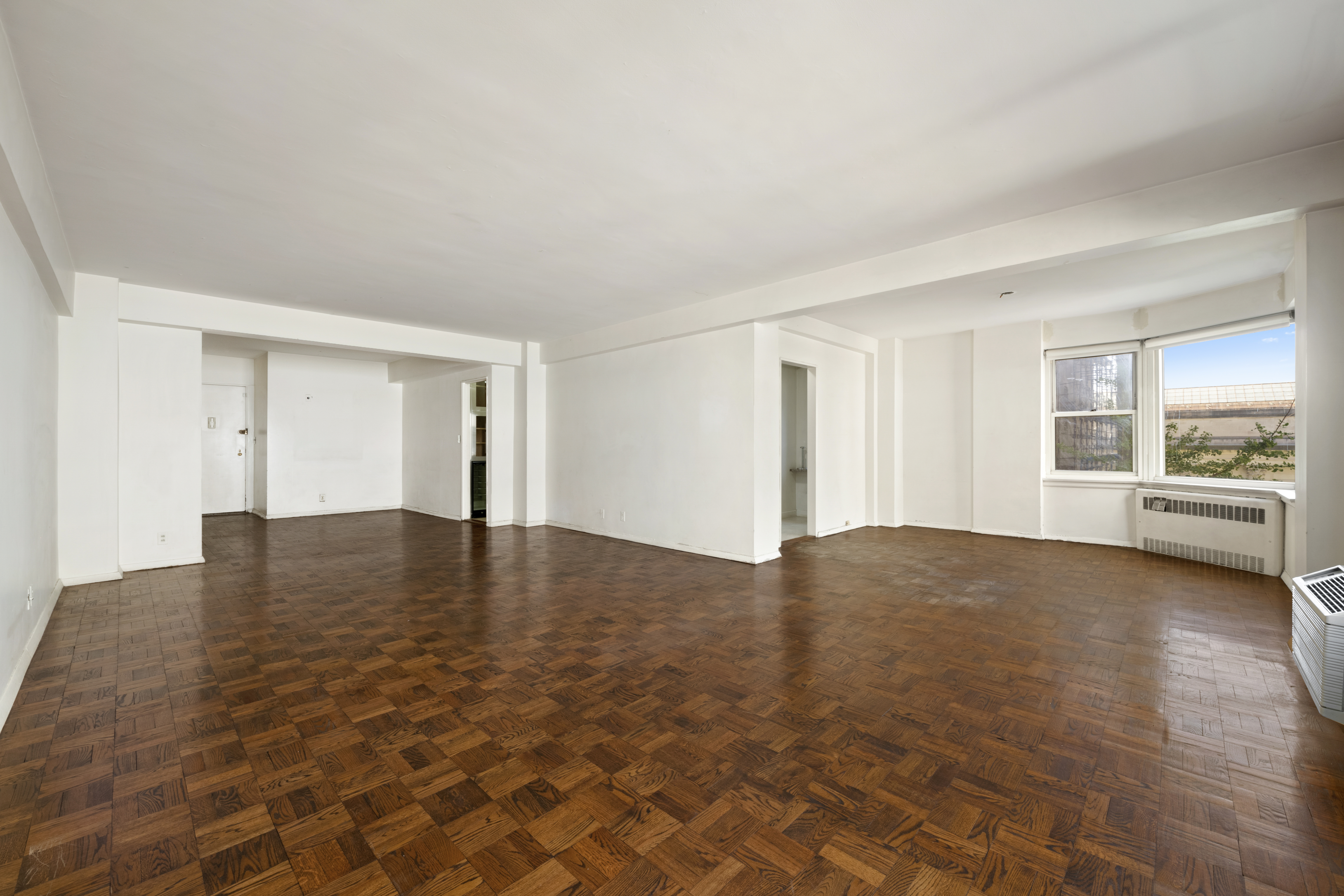 1025 5th Avenue, Unit 7AS Manhattan, NY 10028 - Photo 2 of 16 a view of empty room with wooden floor and floor to ceiling window