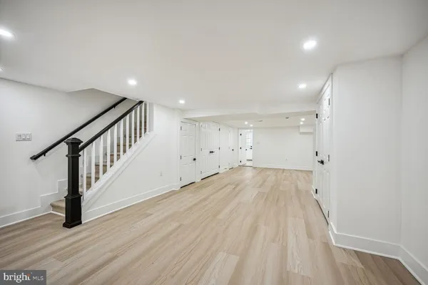 a view of an empty room with wooden floor and stairs
