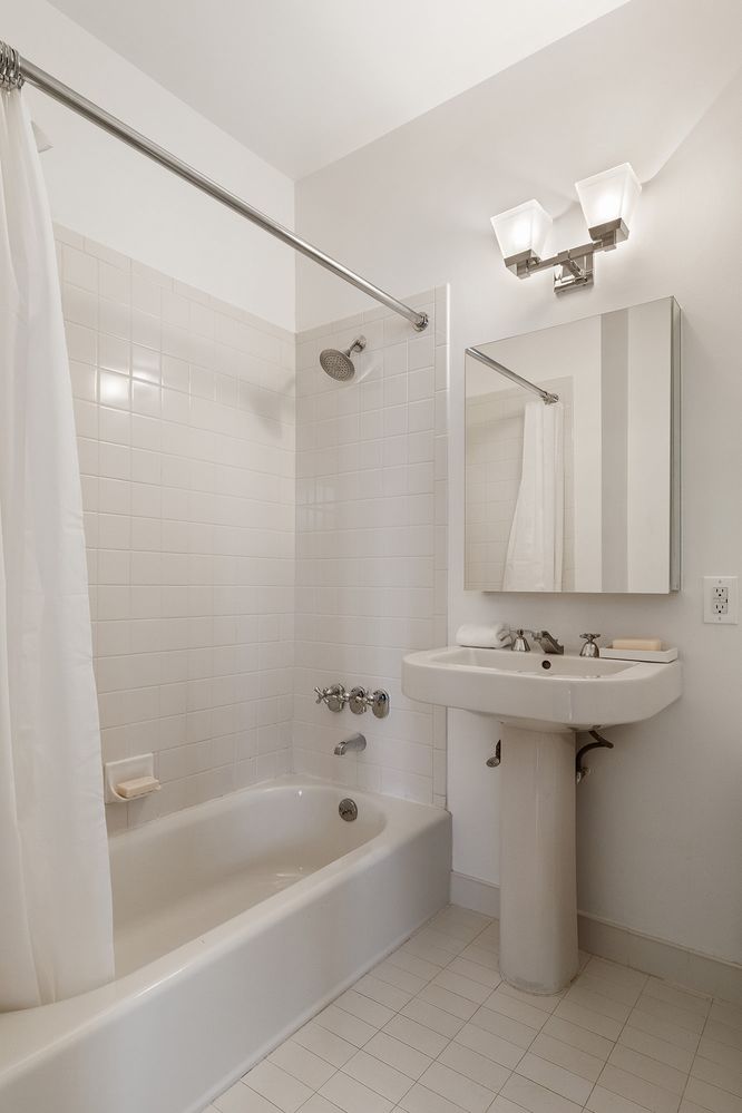 a bathroom with a sink and mirror with bathtub