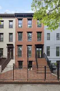 a front view of a house with a tree
