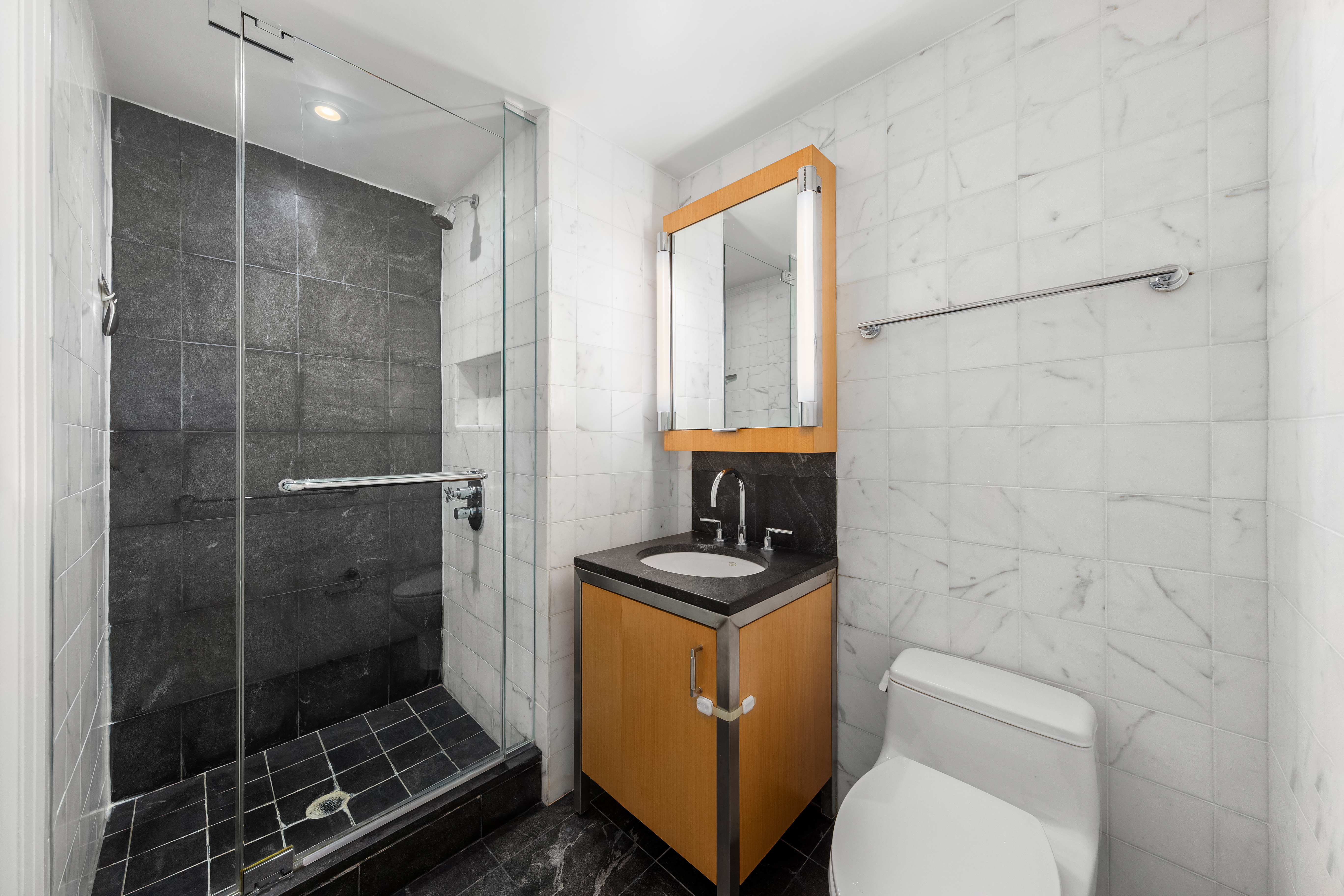 100 West 58th Street, Unit 9B Manhattan, NY 10019 - Photo 7 of 8 a bathroom with a toilet a sink and a shower