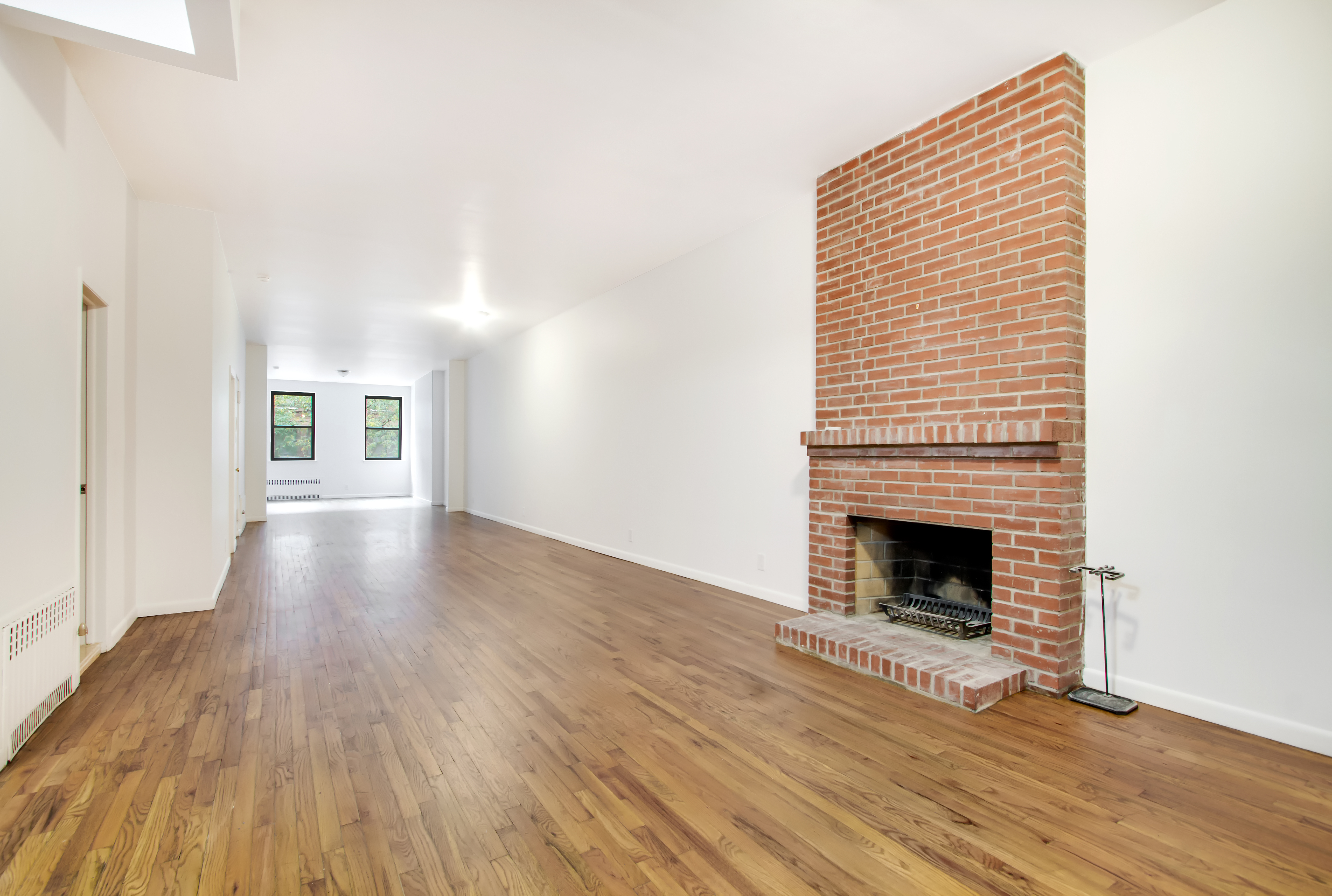248 3rd Avenue, Unit 3 Manhattan, NY 10010 - Photo 1 of 5 a view of an empty room with wooden floor fireplace and a window