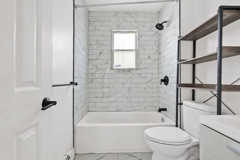 a bathroom with a bathtub shower sink vanity and toilet