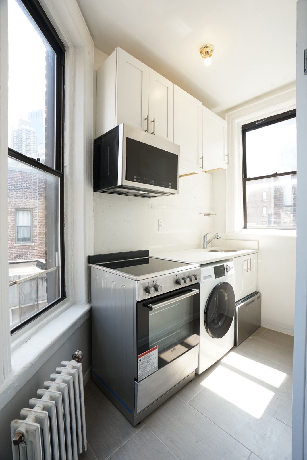 826 9th Avenue, Unit 5RS Manhattan, NY 10019 - Photo 9 of 15 a kitchen with stainless steel appliances a stove microwave and sink