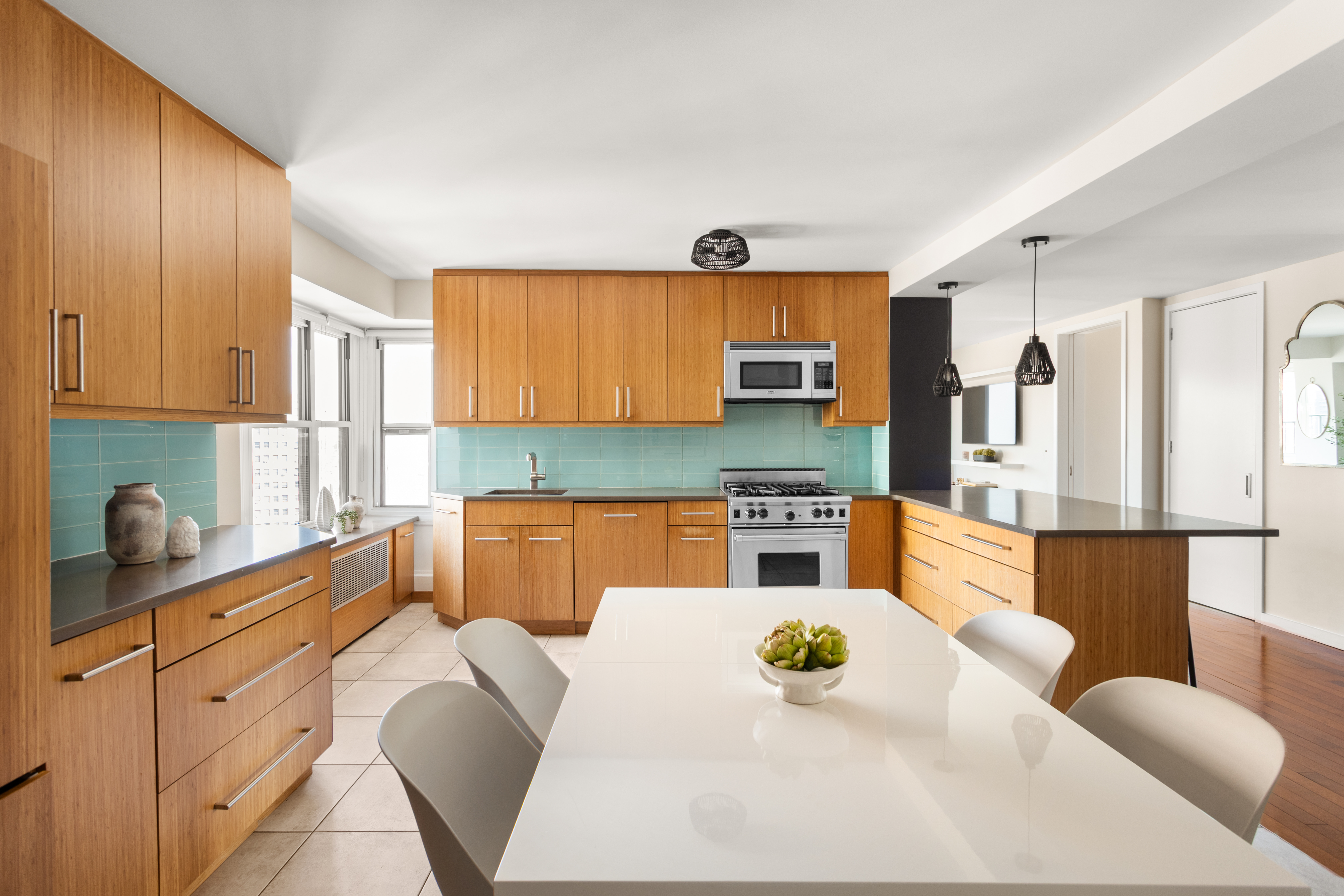 417 Grand Street, Unit D1801 Manhattan, NY 10002 - Photo 6 of 23 a kitchen with stainless steel appliances kitchen island granite countertop a table and chairs in it