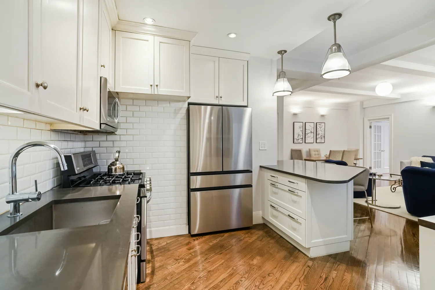 a kitchen with granite countertop a refrigerator a stove a sink and white cabinets with wooden floor