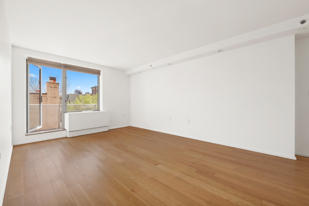 2280 Frederick Douglass Boulevard, Unit 6A Manhattan, NY 10027 - Photo 9 of 13 a view of an empty room with wooden floor and a window
