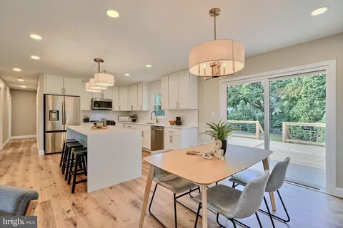 a view of a dining room and livingroom with furniture wooden floor a chandelier