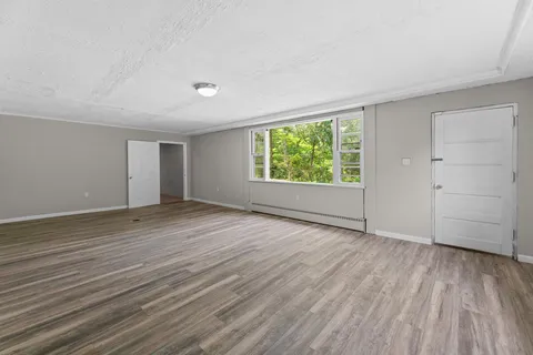 an empty room with wooden floor and windows