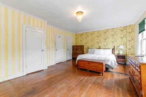 a spacious bedroom with a bed and wooden floor