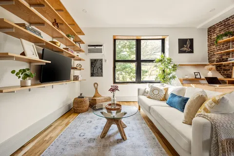 a living room with furniture a flat screen tv and a floor to ceiling window