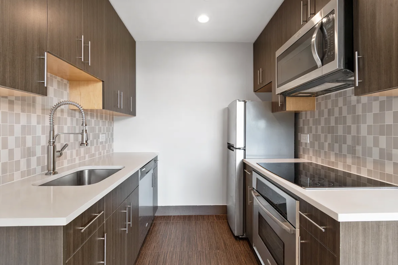 5-43 48th Avenue, Unit 5E Queens, NY 11101 - Photo 2 of 9 a kitchen with granite countertop a sink and a stove top oven