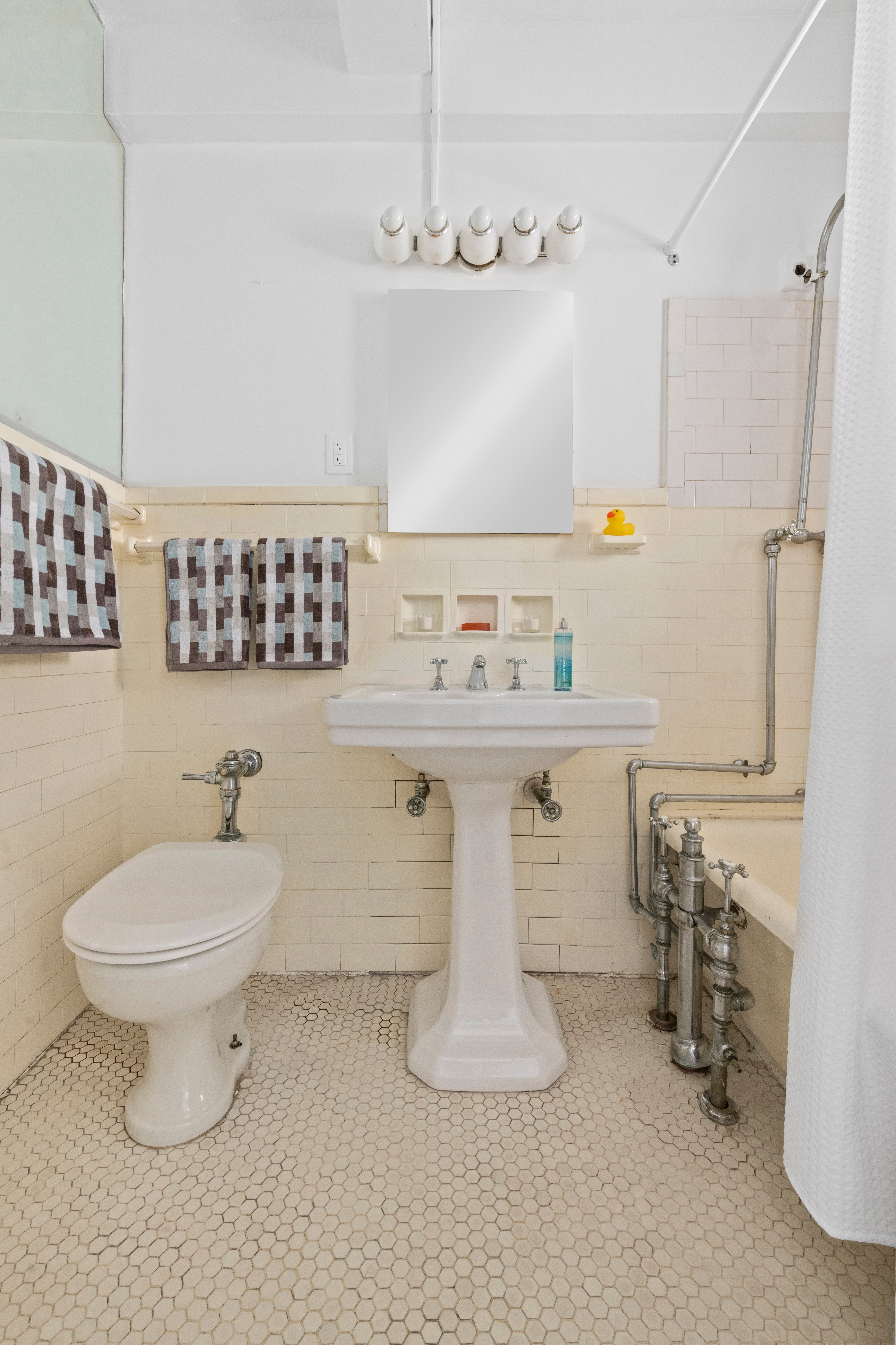 1 West 67th Street, Unit 501/502 Manhattan, NY 10023 - Photo 13 of 19 a bathroom with a sink a toilet and mirror