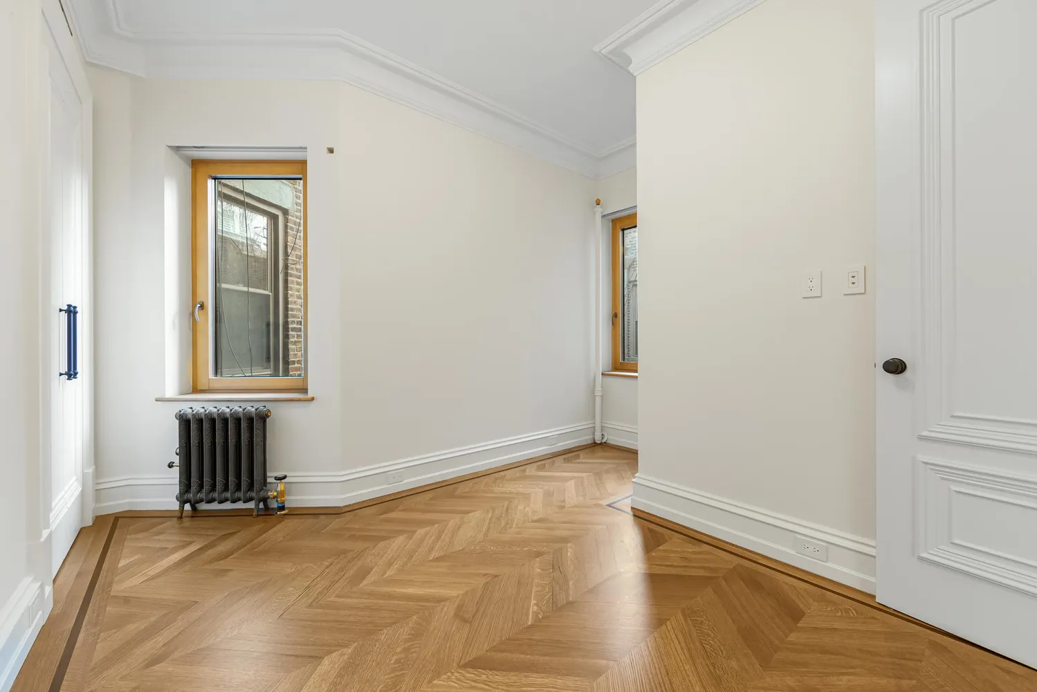 a view of an empty room with window and wooden floor