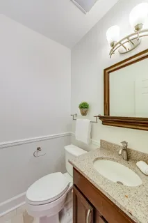 a bathroom with a granite countertop toilet sink and mirror
