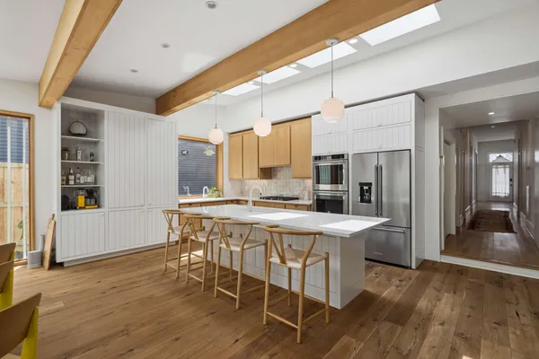 a kitchen with stainless steel appliances kitchen island granite countertop a stove a refrigerator a sink a dining table and chairs with wooden floor