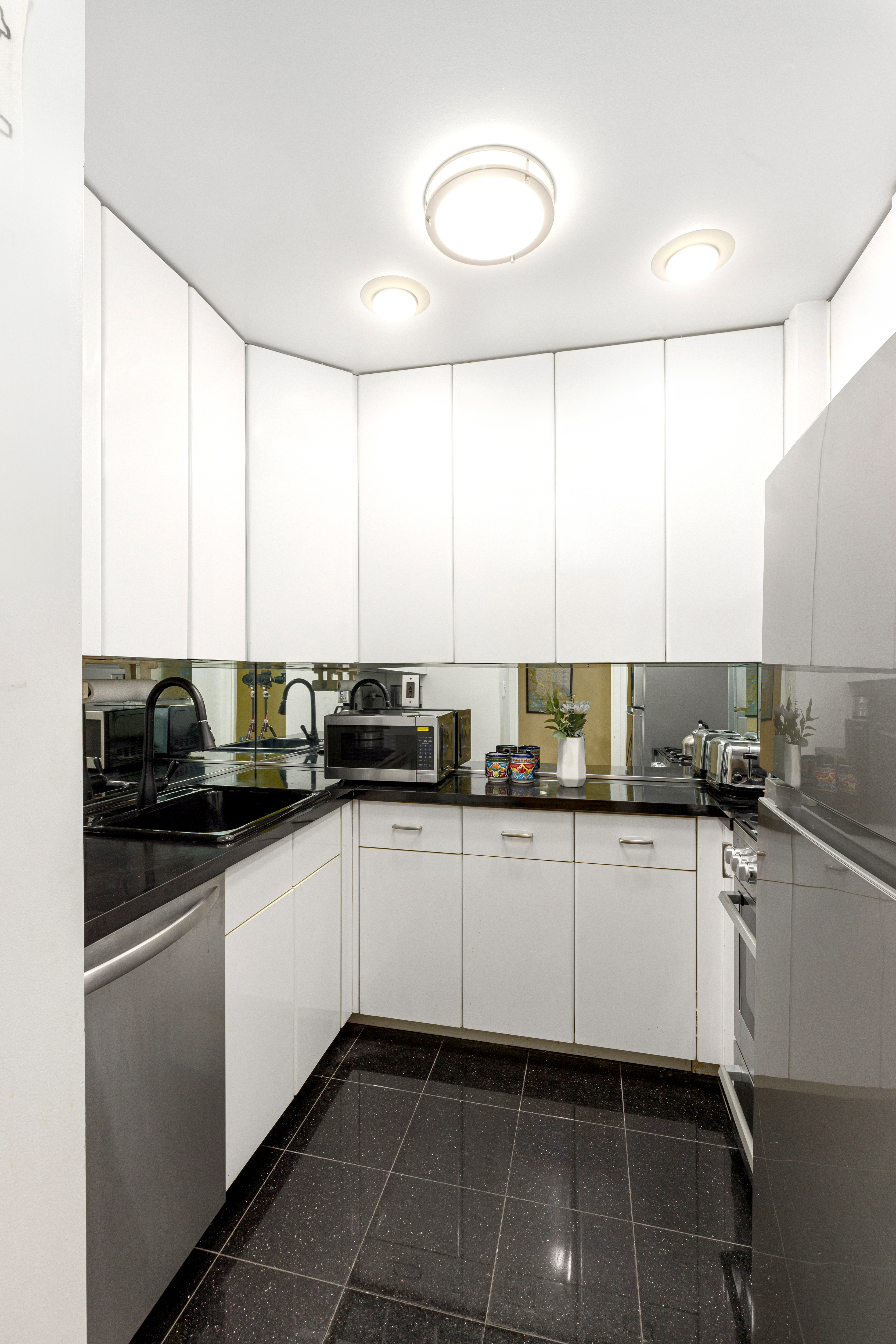 201 West 70th Street, Unit 17A Manhattan, NY 10023 - Photo 4 of 20 a kitchen with stainless steel appliances a sink a stove a microwave and cabinets