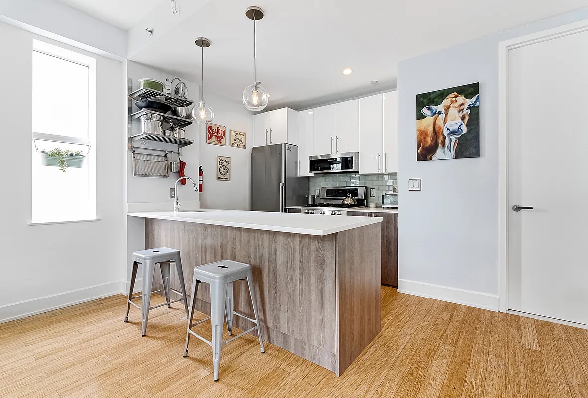 12 Monitor Street, Unit 3B Brooklyn, NY 11222 - Photo 4 of 11 a kitchen with kitchen island white cabinets and stainless steel appliances