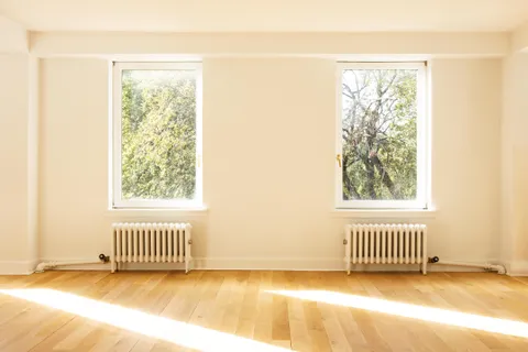 an empty room with a window and a wooden floor