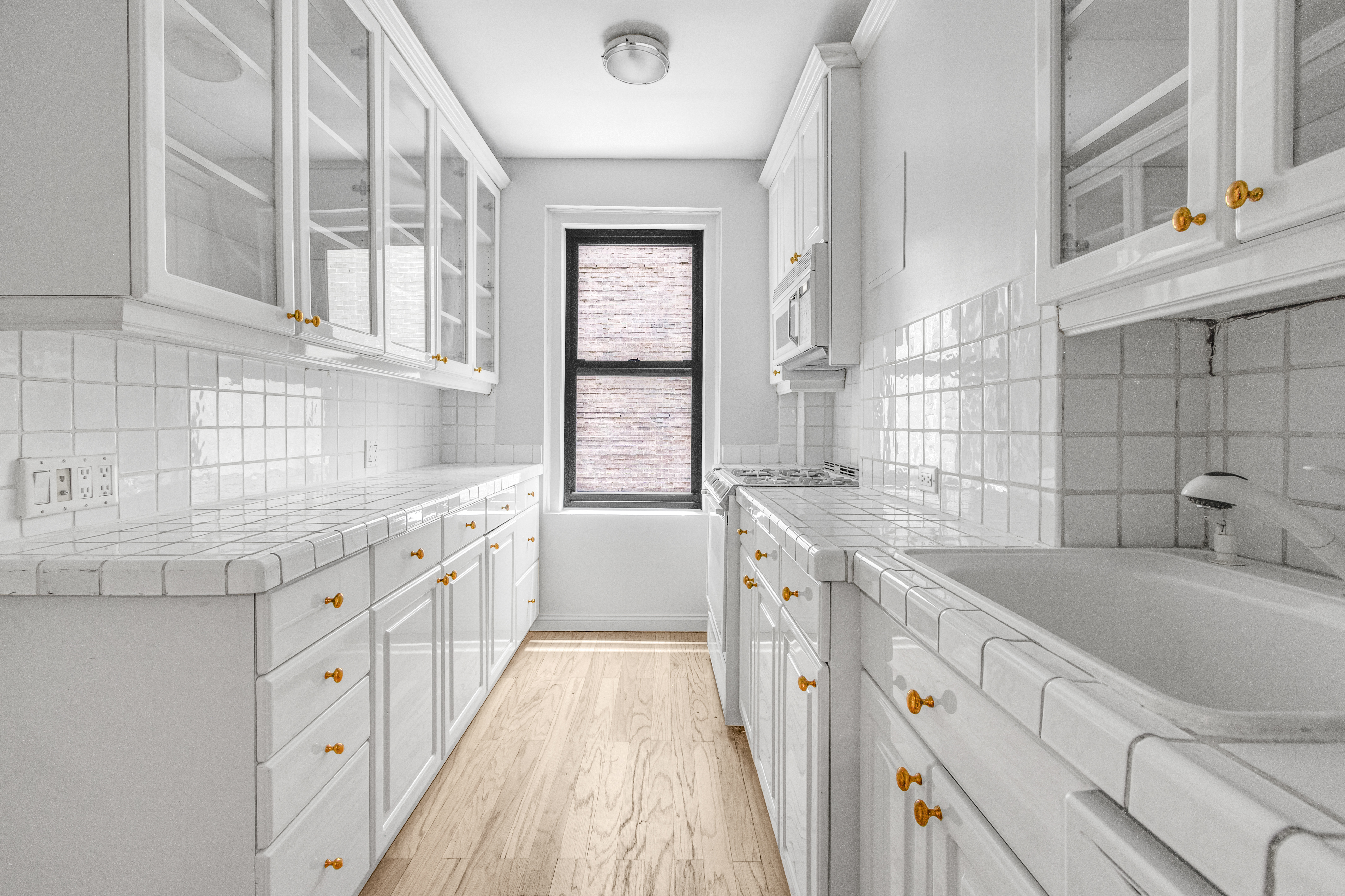 127 West 96th Street, Unit 4D Manhattan, NY 10025 - Photo 5 of 14 a kitchen with granite countertop a sink dishwasher a stove and white cabinets with wooden floor