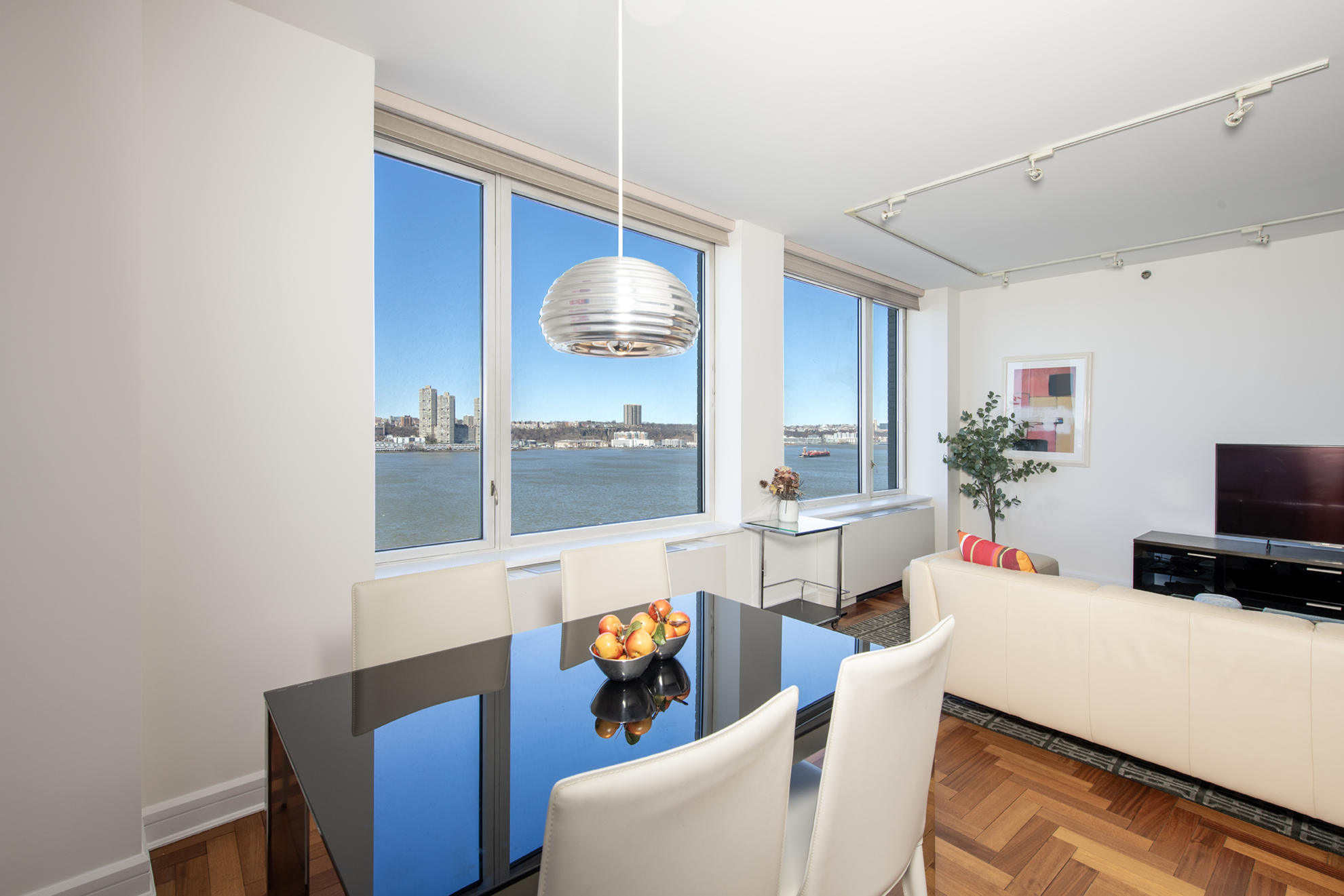 220 Riverside Boulevard, Unit 9K Manhattan, NY 10069 - Photo 2 of 8 a living room with furniture a flat screen tv and a window