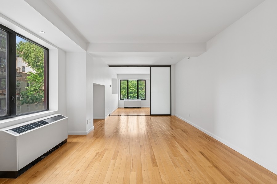 189 Avenue C, Unit 4D Manhattan, NY 10009 - Photo 9 of 17 a view of an empty room with wooden floor and a window
