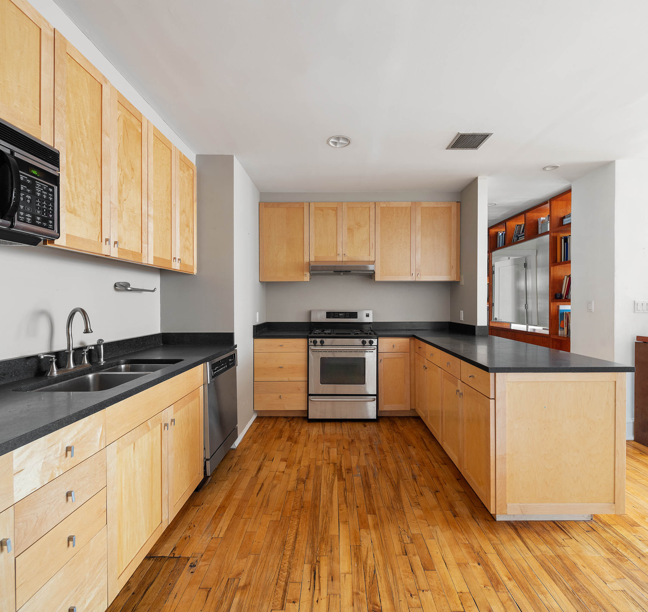 126 West 22nd Street, Unit 5N Manhattan, NY 10011 - Photo 3 of 13 a kitchen with granite countertop wooden floors a stove and a microwave