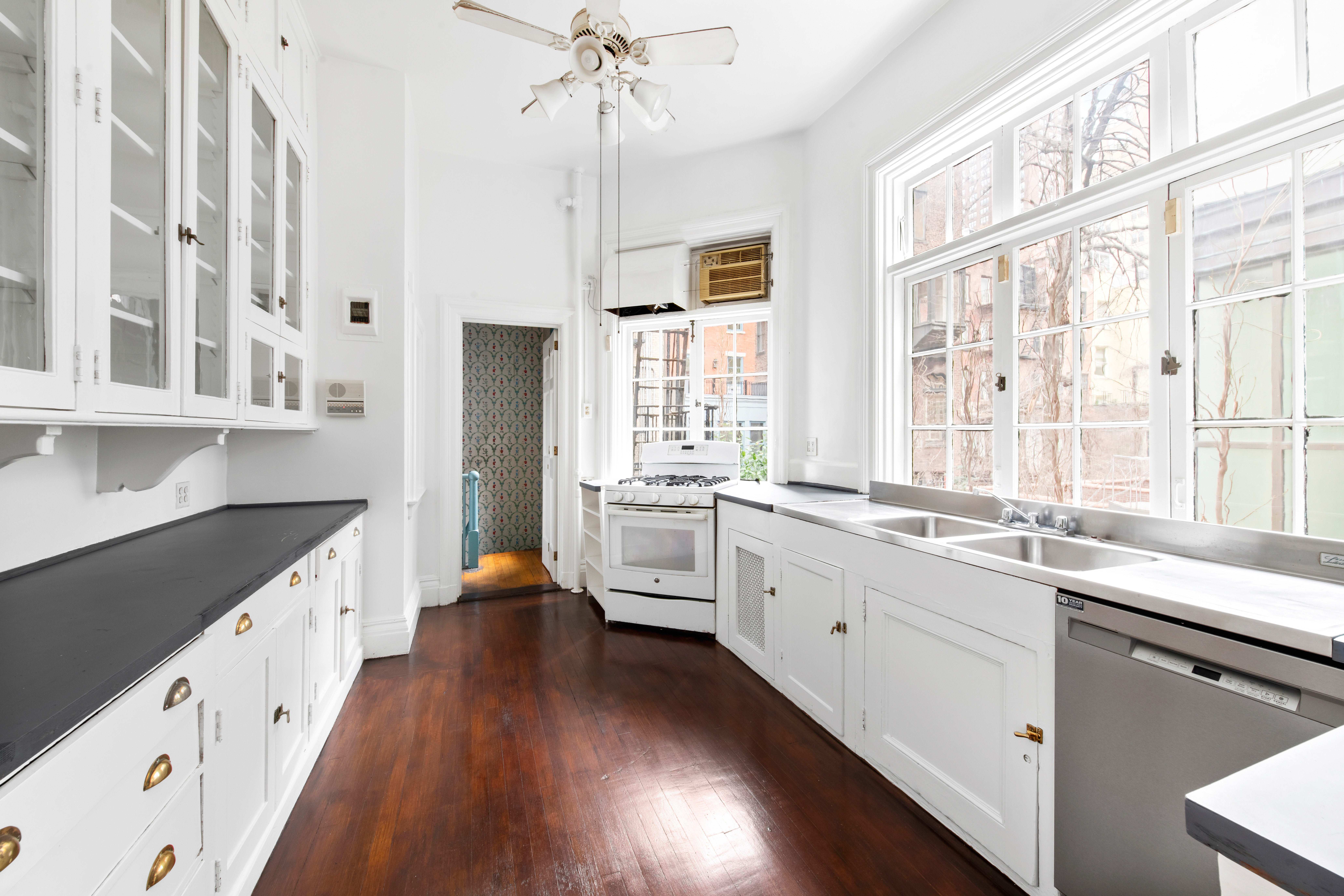 155 East 70th Street Manhattan, NY 10021 - Photo 4 of 27 a large white kitchen with granite countertop a large counter top space a sink a window and appliances