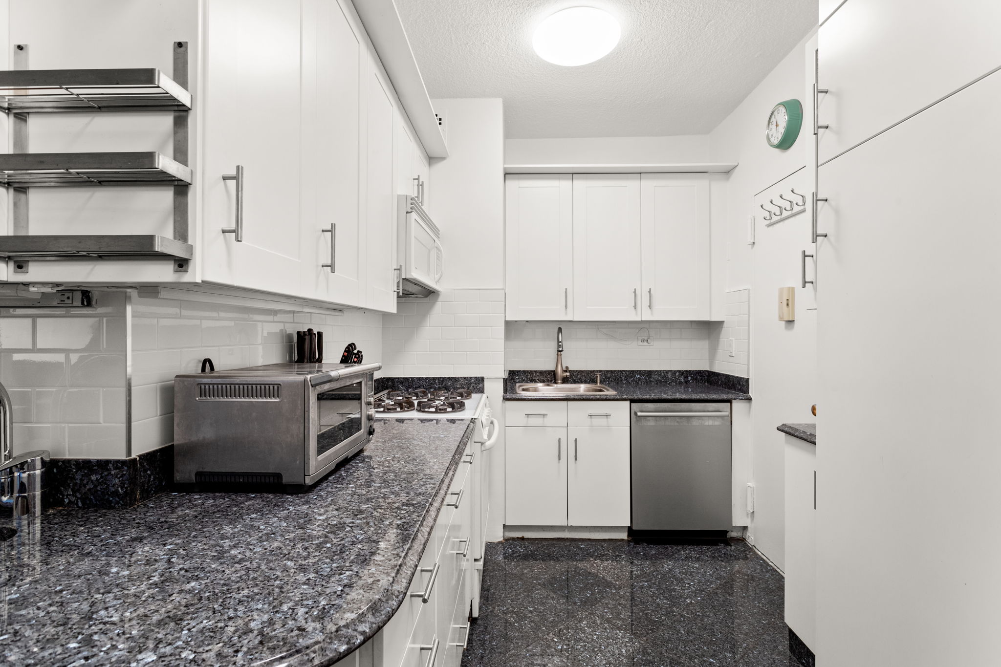 60 East 8th Street, Unit 24J Manhattan, NY 10003 - Photo 8 of 16 a kitchen with stainless steel appliances granite countertop a stove a sink and a refrigerator