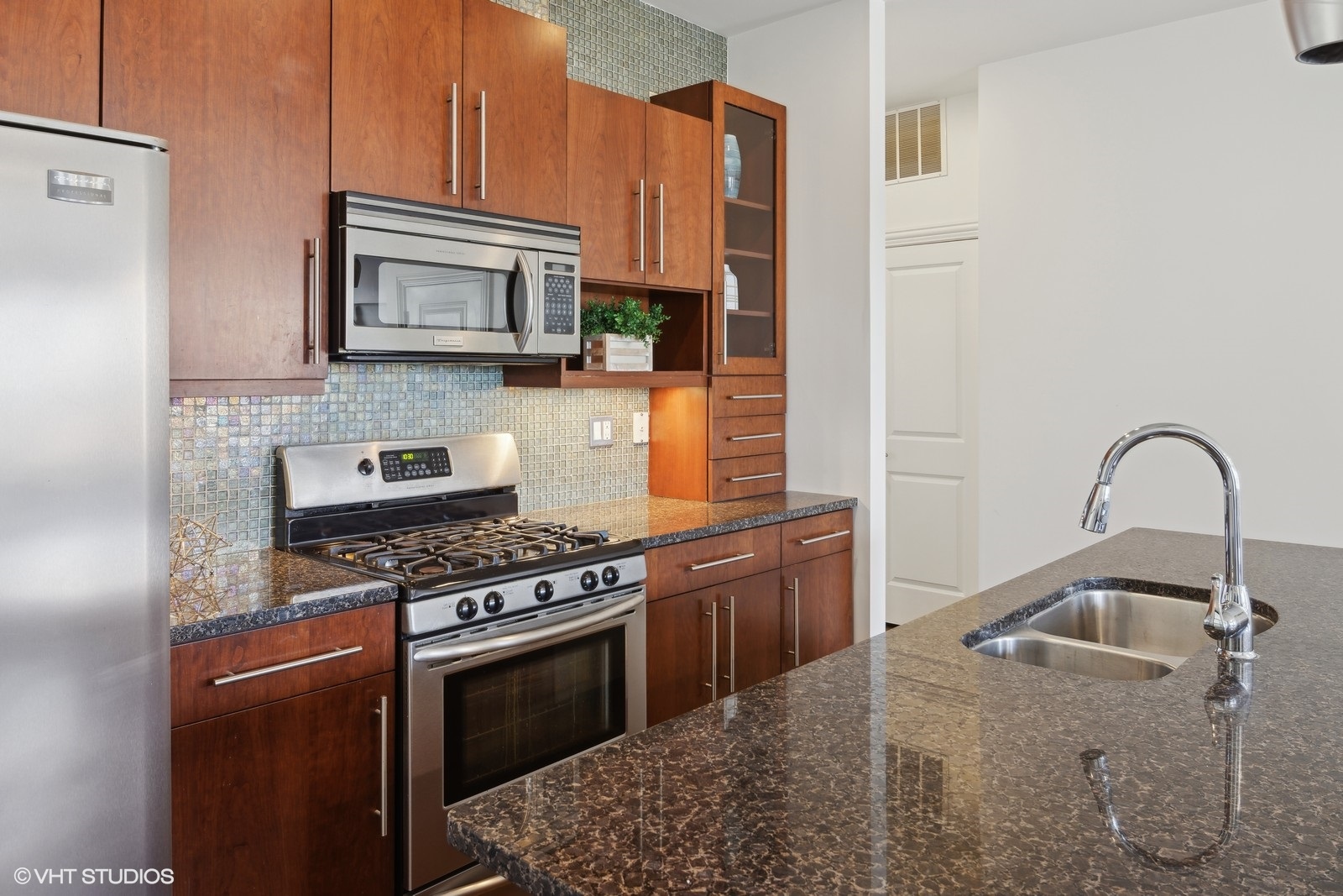 1227 East 46th Street, Unit 2E Chicago, IL 60653 - Photo 7 of 16 a kitchen with stainless steel appliances granite countertop a stove a sink and a microwave