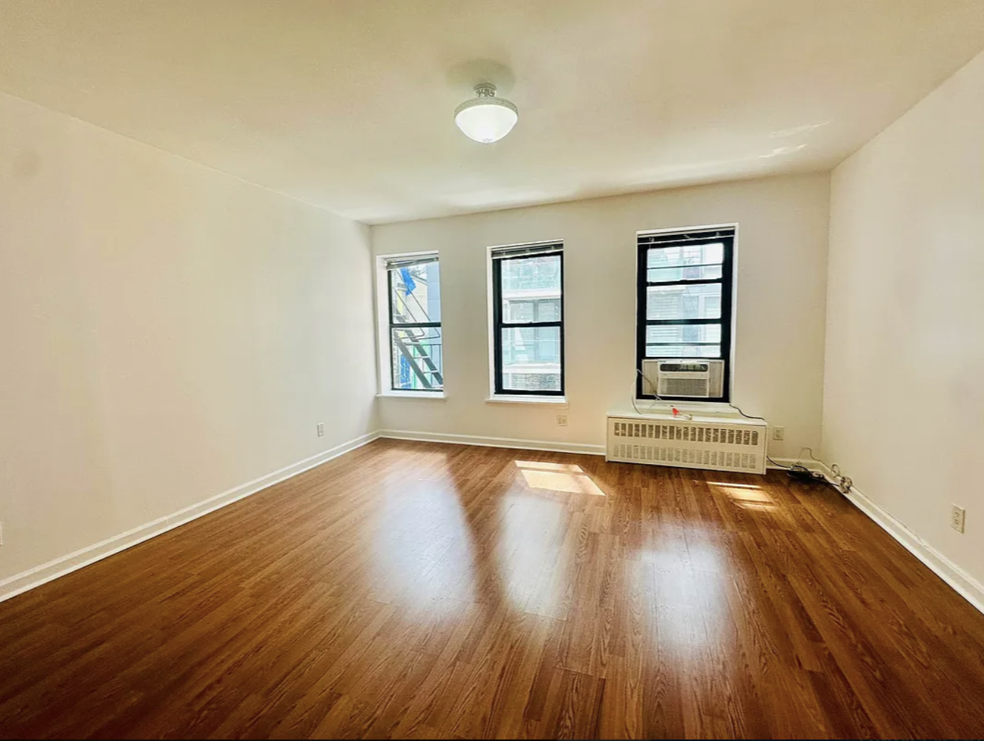 305 East 95th Street, Unit 6E Manhattan, NY 10128 - Photo 4 of 9 an empty room with wooden floor and windows