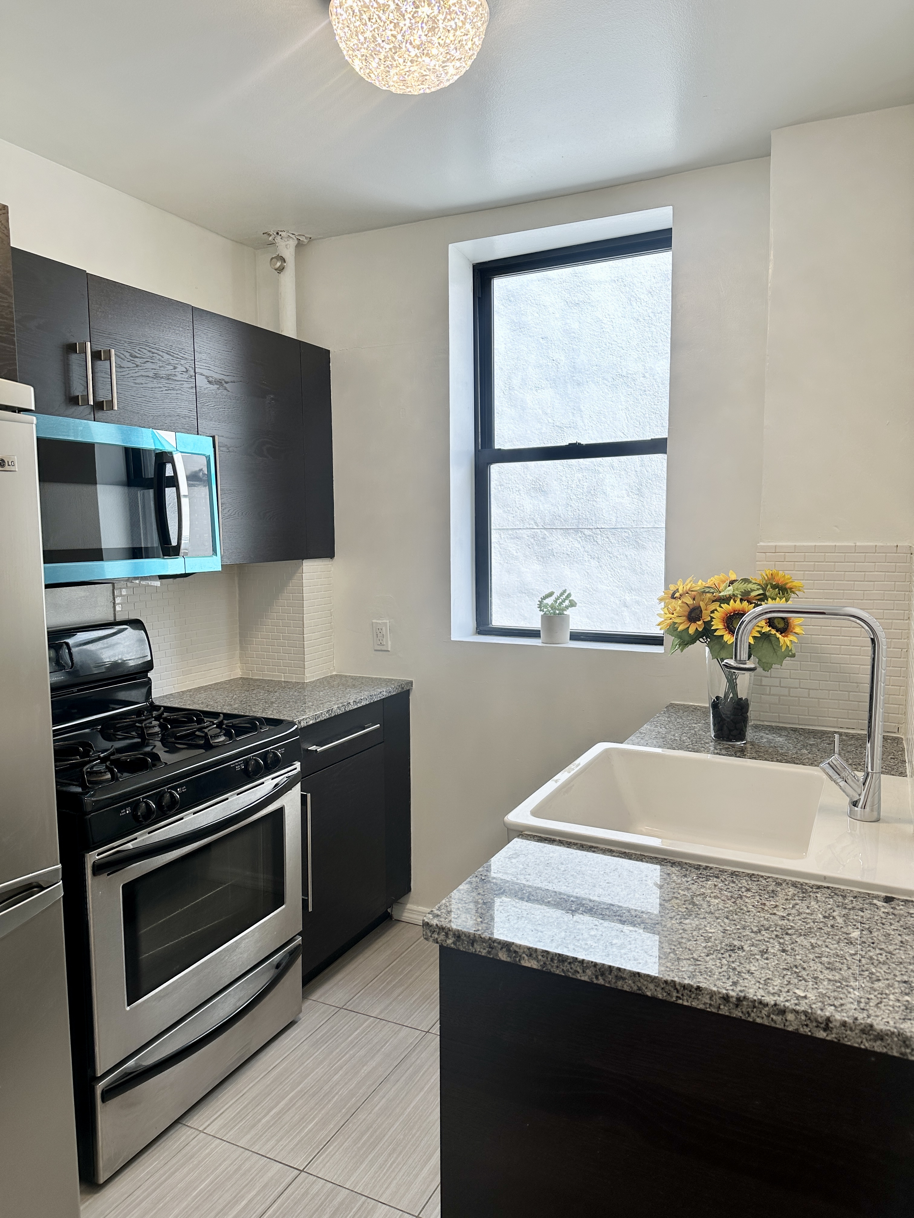 246 East 51st Street, Unit 22 Manhattan, NY 10022 - Photo 5 of 9 a kitchen with granite countertop stainless steel appliances a sink stove and microwave