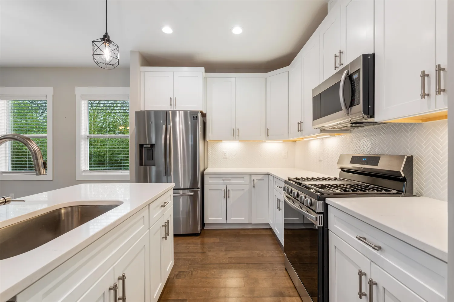 a kitchen with stainless steel appliances granite countertop a sink a stove a refrigerator cabinets and a microwave