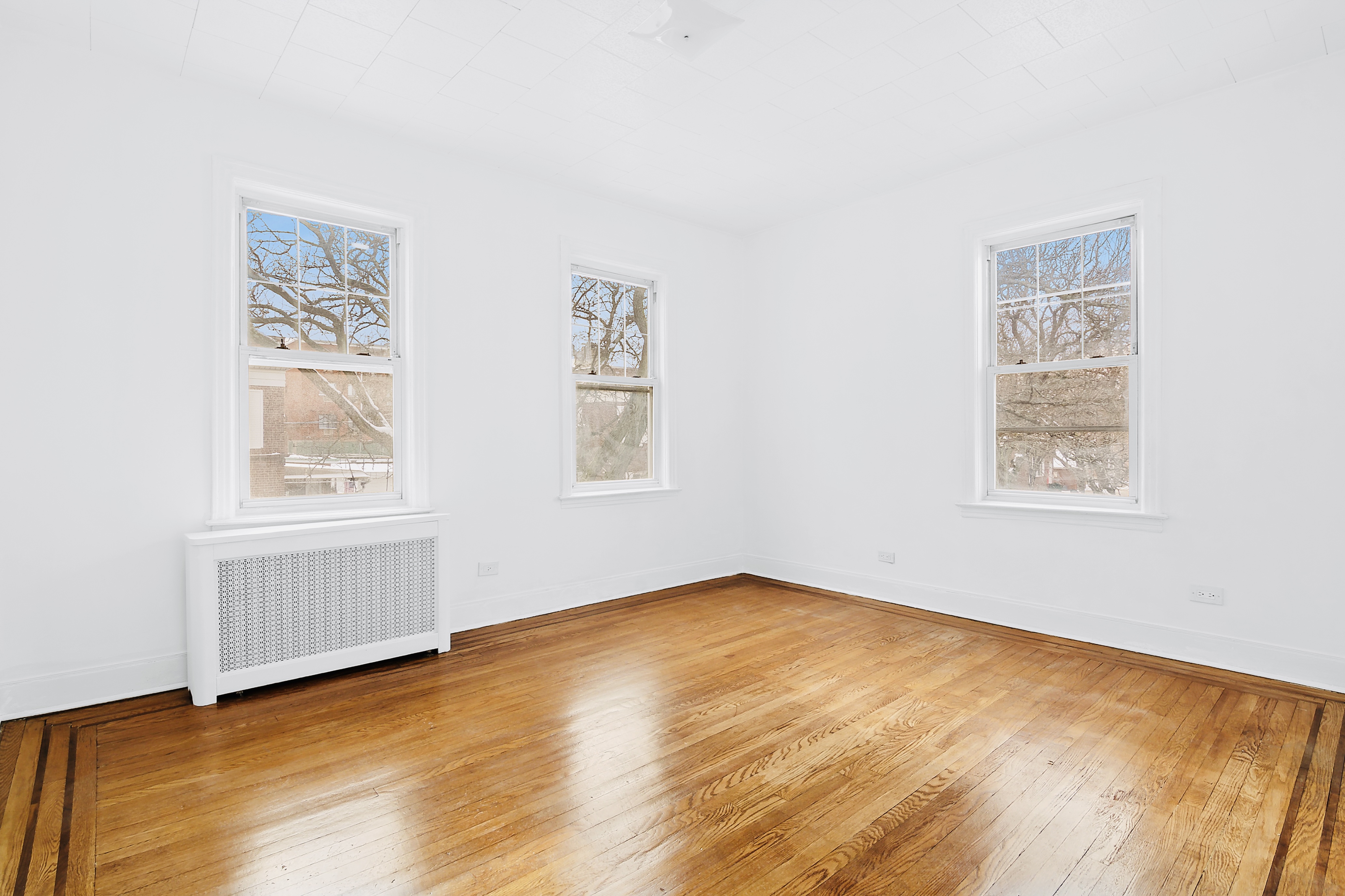 63-33 Haring Street, Unit 2F Queens, NY 11374 - Photo 5 of 7 a view of an empty room with a window and wooden floor