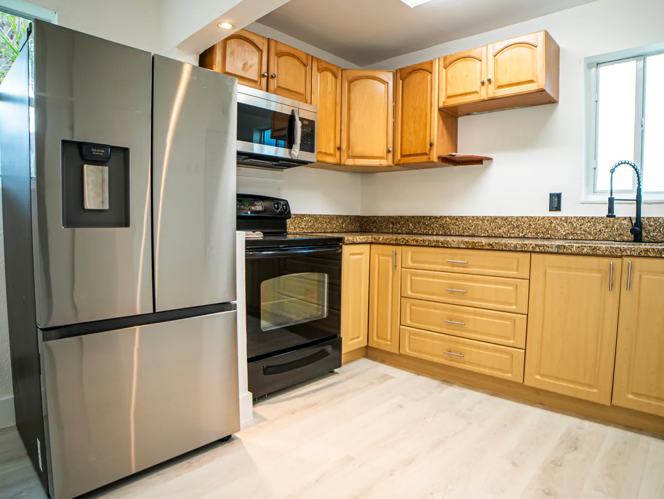 a kitchen with stainless steel appliances granite countertop a refrigerator a microwave a sink and cabinets