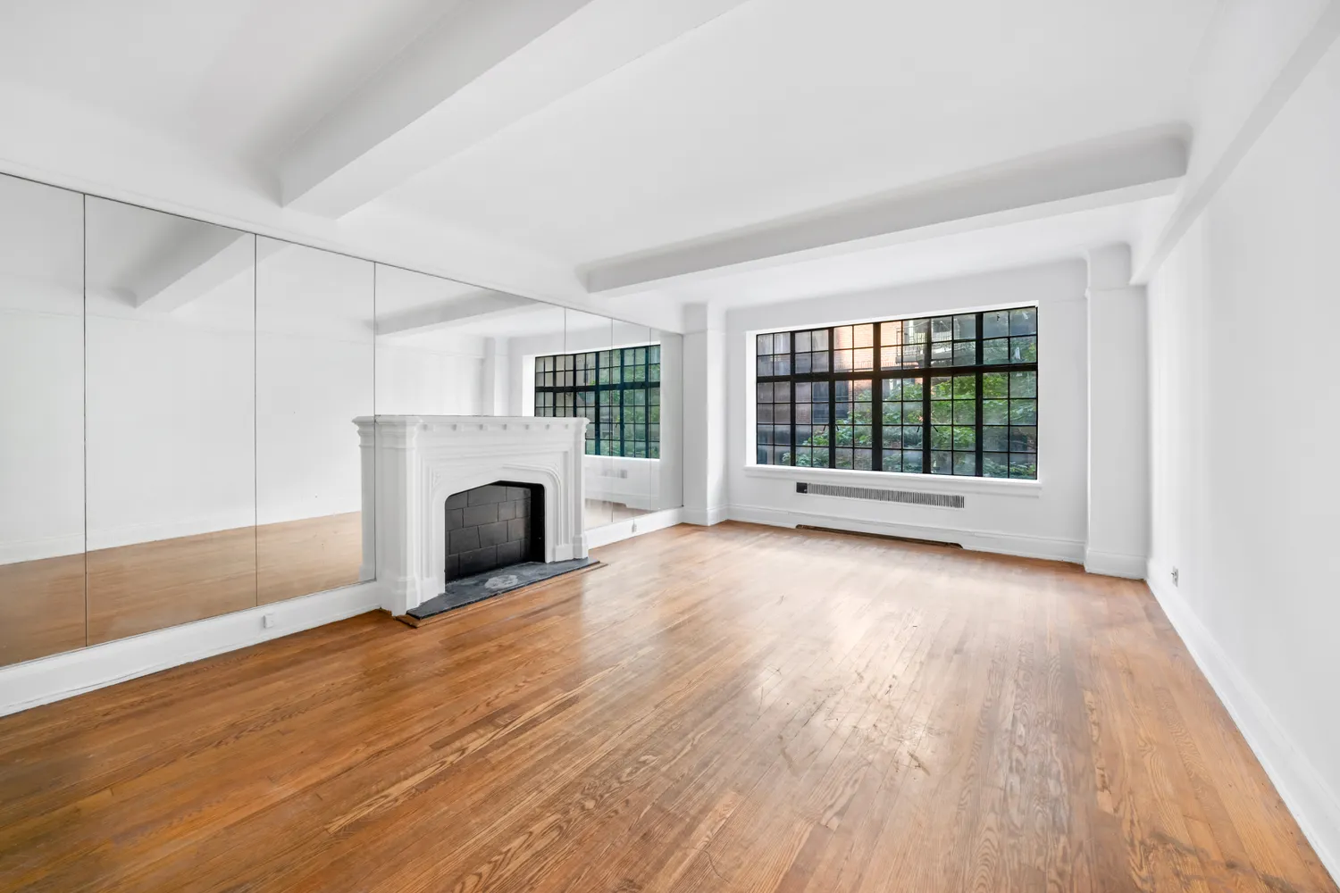 an empty room with wooden floor fireplace and windows