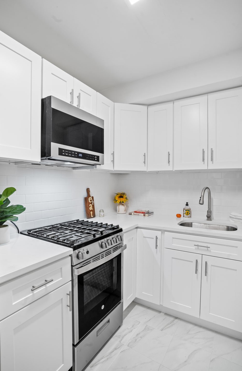150 East 61st Street, Unit 8B Manhattan, NY 10065 - Photo 20 of 30 a kitchen with granite countertop white cabinets a sink and white appliances