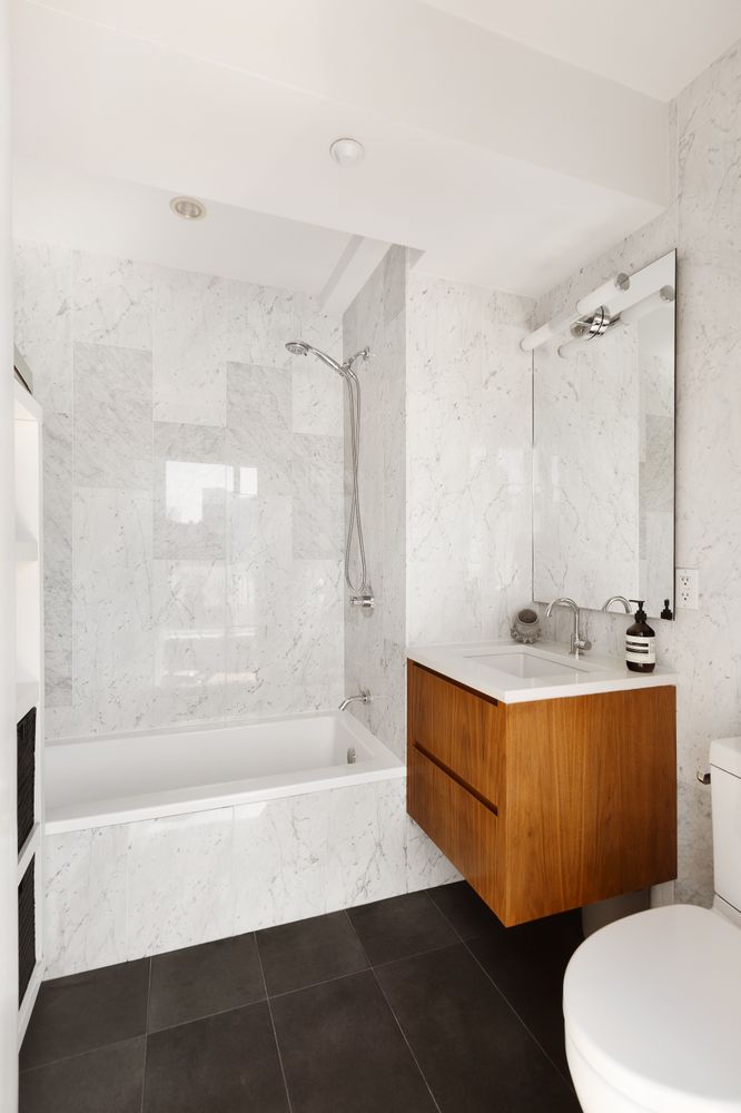 142 North 1st Street, Unit PH Brooklyn, NY 11249 - Photo 11 of 15 a bathroom with a sink a toilet a mirror and bathtub