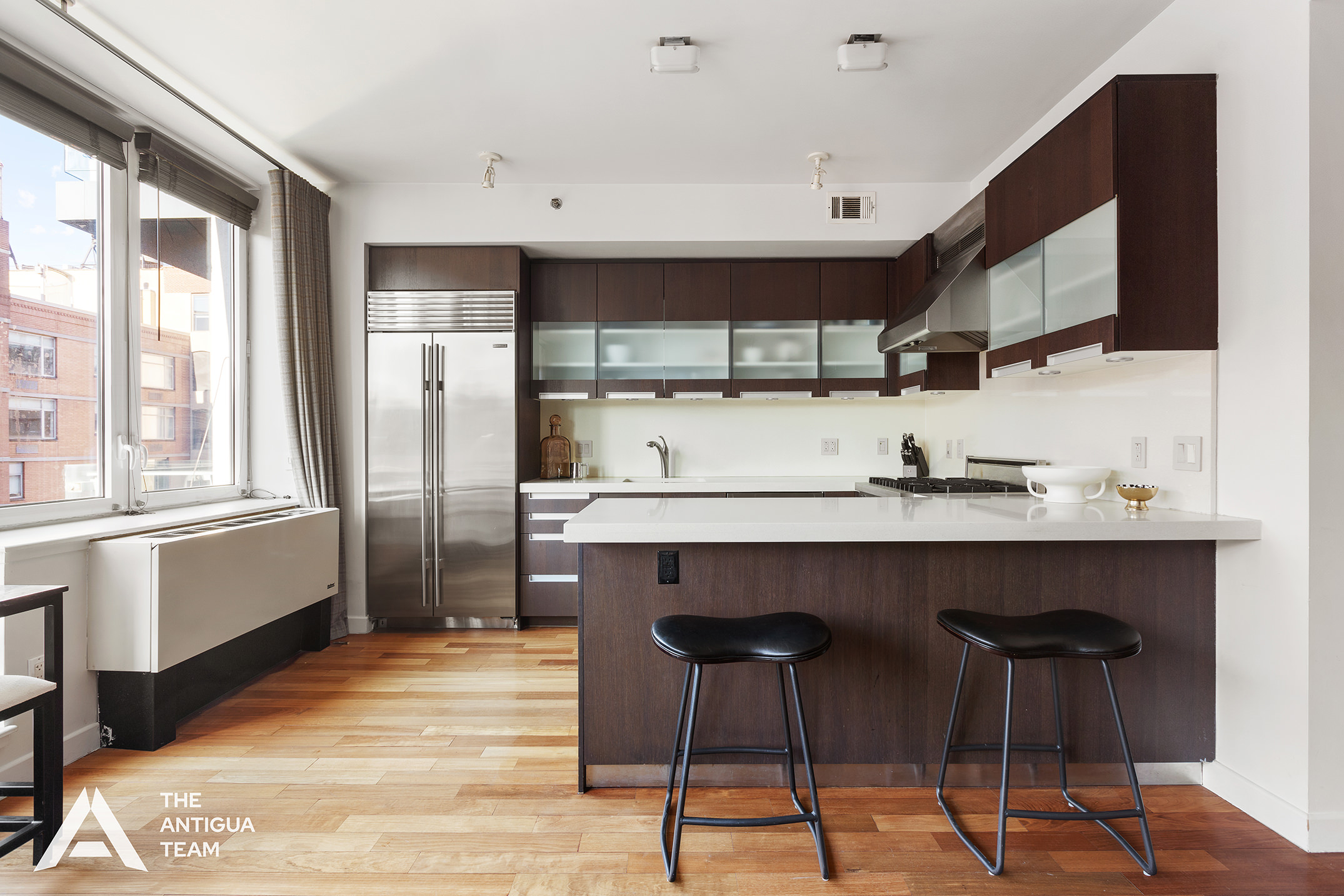 125 West 21st Street, Unit 12A Manhattan, NY 10011 - Photo 4 of 16 a kitchen with stainless steel appliances a sink and a refrigerator