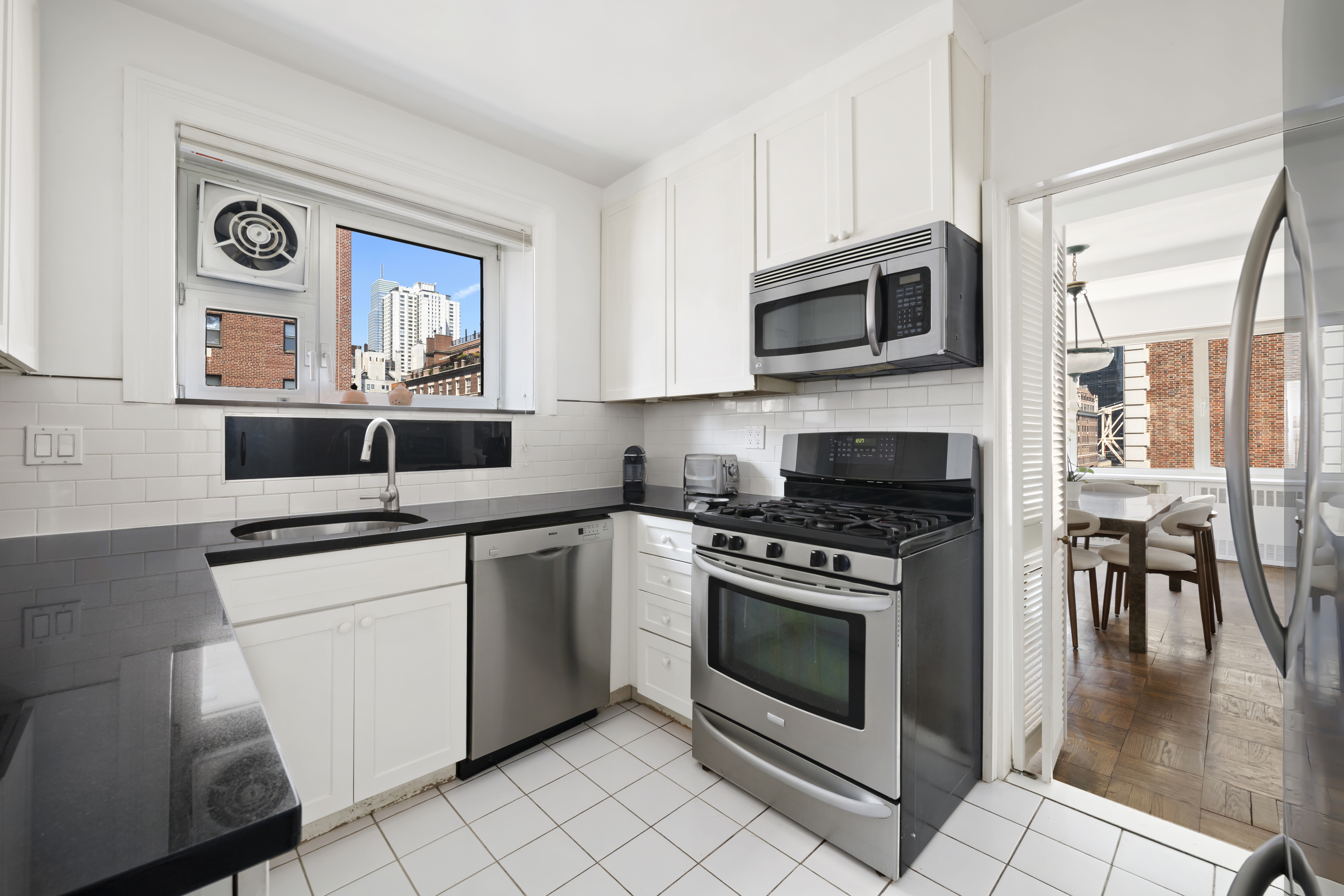 25 Sutton Place South, Unit 16B Manhattan, NY 10022 - Photo 7 of 16 a kitchen with stainless steel appliances a stove a sink and a microwave