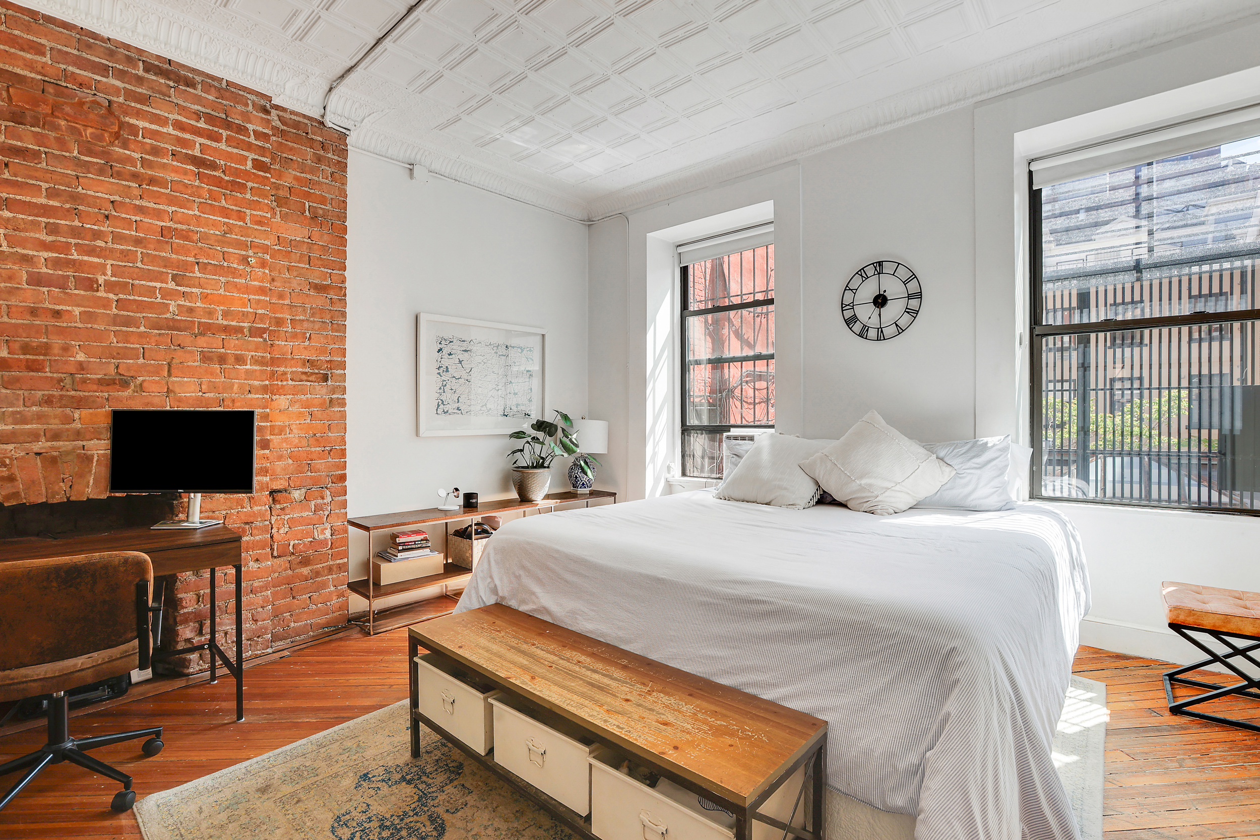 5 Great Jones Street Manhattan, NY 10012 - Photo 6 of 11 a bedroom with a bed a computer on the desk and a potted plant