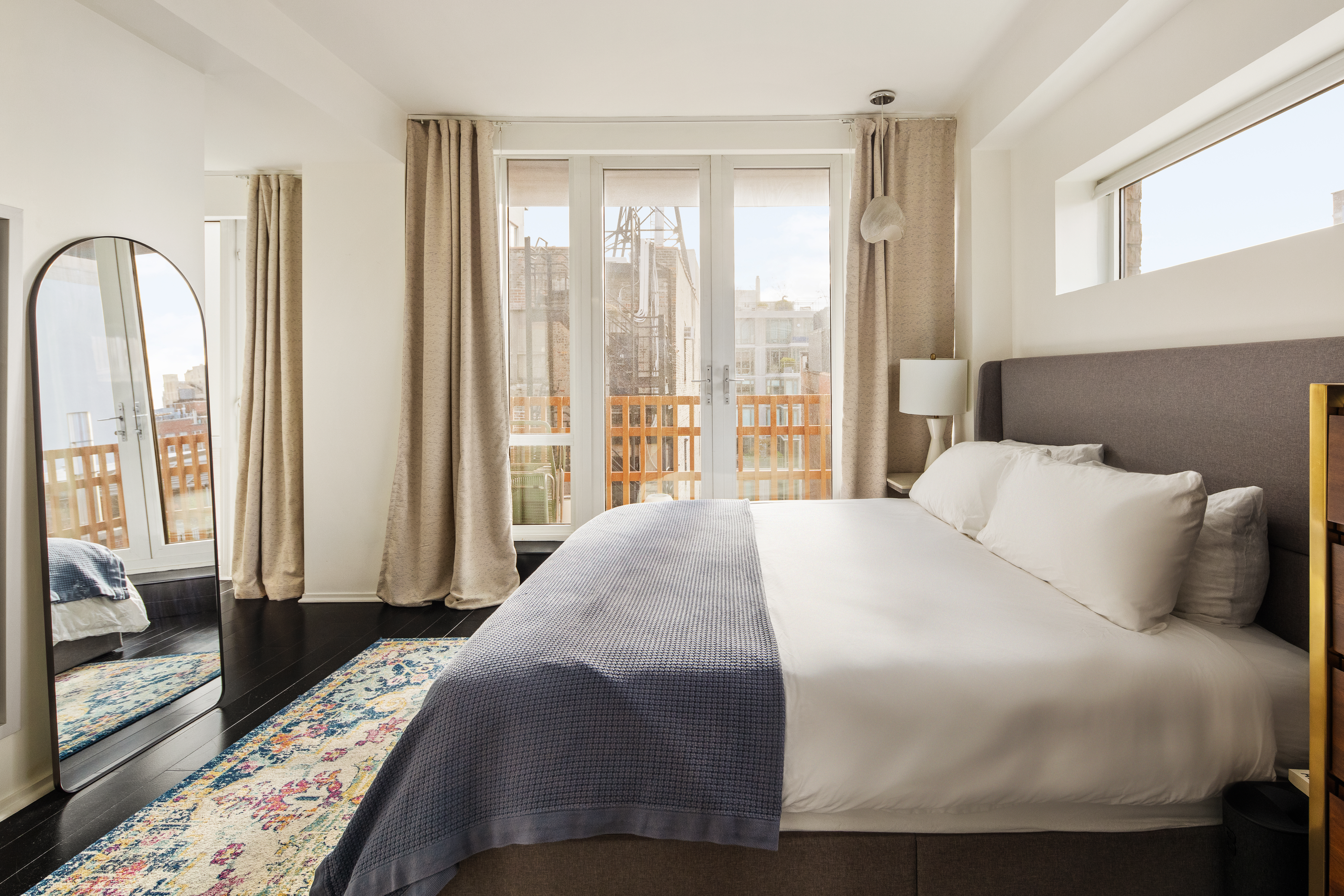 130 West 20th Street, Unit PH11A Manhattan, NY 10011 - Photo 6 of 9 a bedroom with a large bed and a large window with wooden floor