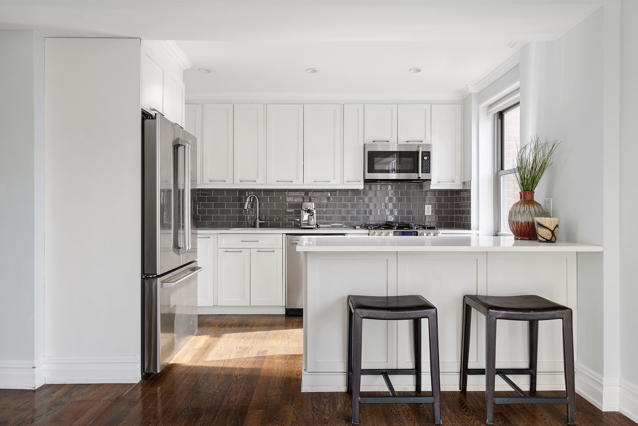 136 East 76th Street, Unit 16DE Manhattan, NY 10021 - Photo 5 of 14 a kitchen with stainless steel appliances granite countertop a refrigerator a stove a sink and white cabinets with wooden floor