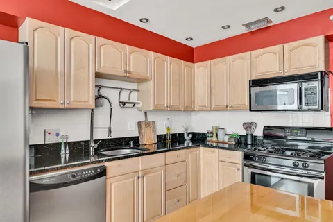 a kitchen with stainless steel appliances kitchen island granite countertop a refrigerator a stove and a sink with wooden floor