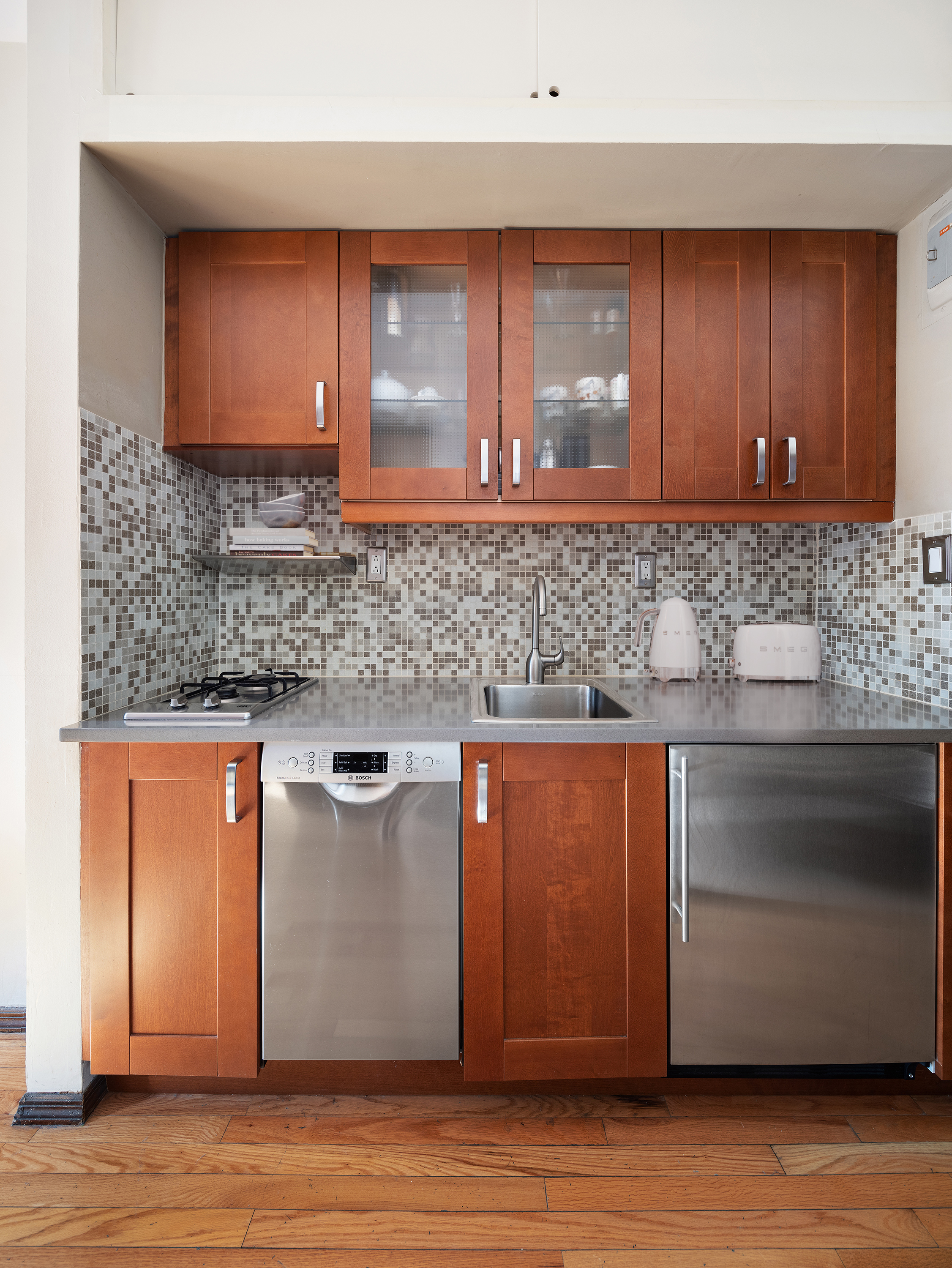 438 West 49th Street, Unit 5B Manhattan, NY 10019 - Photo 5 of 7 a kitchen with stainless steel appliances granite countertop wooden cabinets a oven and granite counter tops with wooden floors