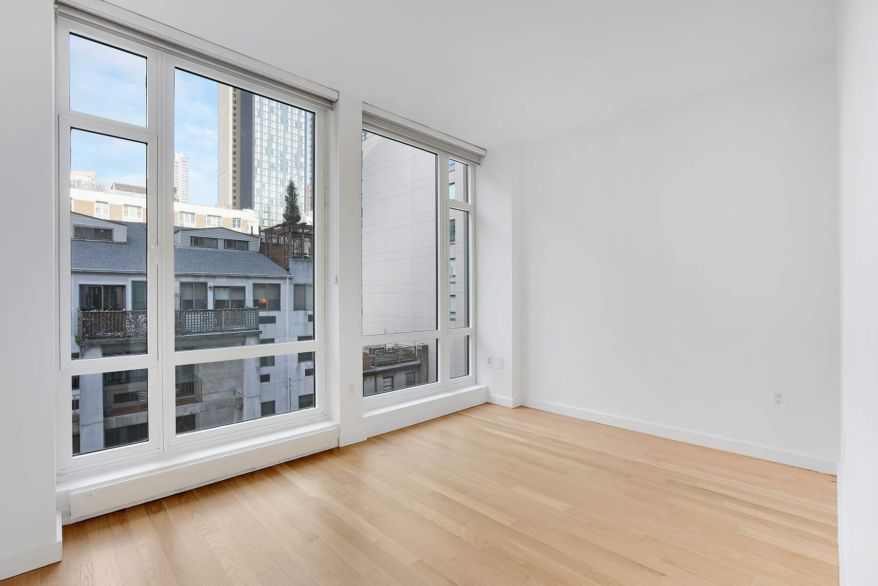 133 West 22nd Street, Unit 7H Manhattan, NY 10011 - Photo 9 of 21 an empty room with wooden floor and windows